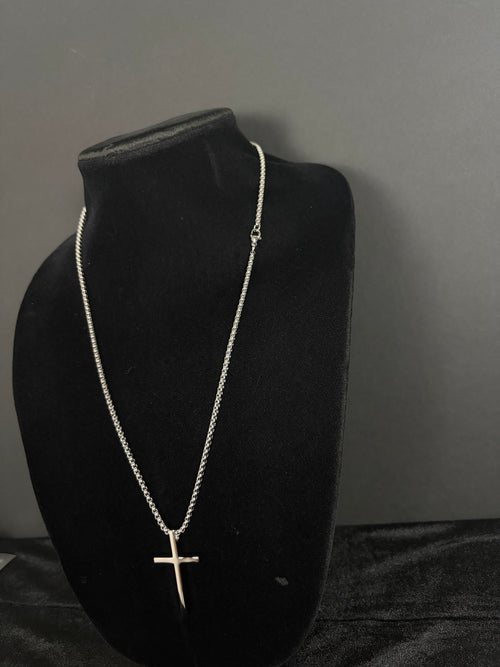 Silver-tone cross necklace — angled view on a black display